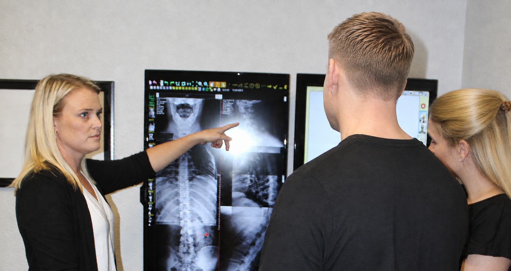 Dr. Caitlin Zimmer explaining spinal X-rays to patients at Corrective Spinal Care of Texas